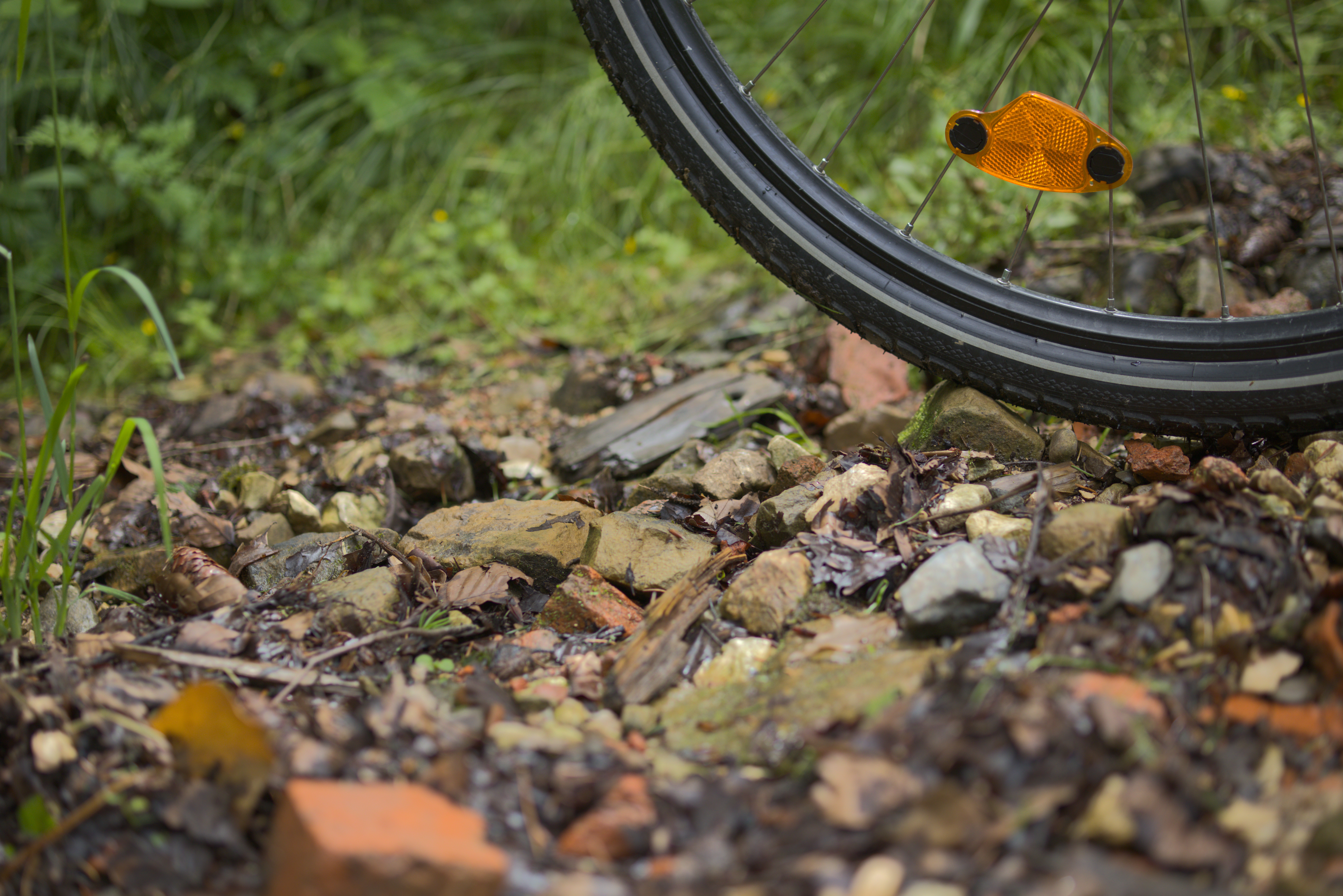 Trail made up of medium-sized rocks beneath the wheel of a bicycle, up close.