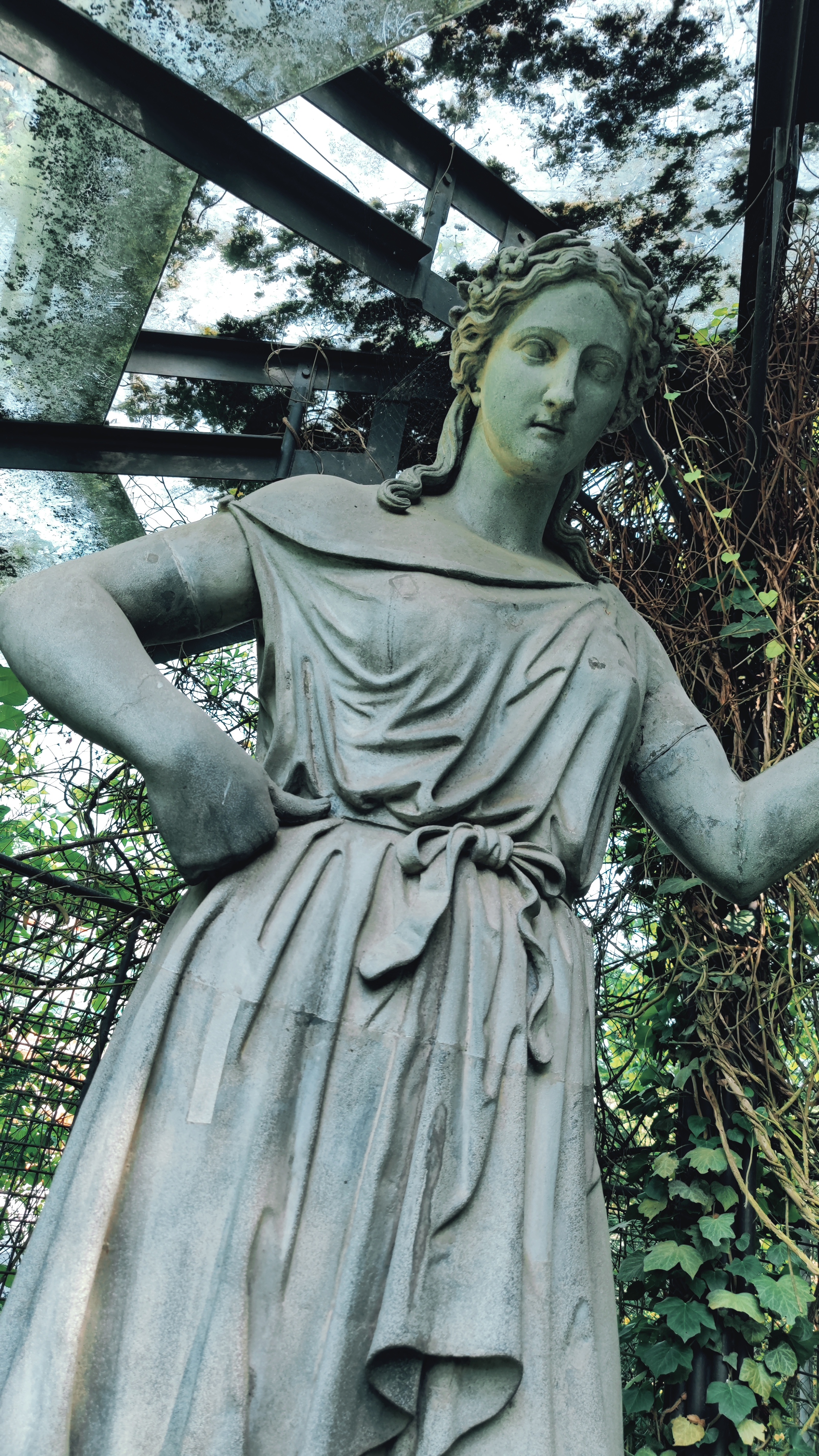 A statue of a woman with some roof structure above her head.