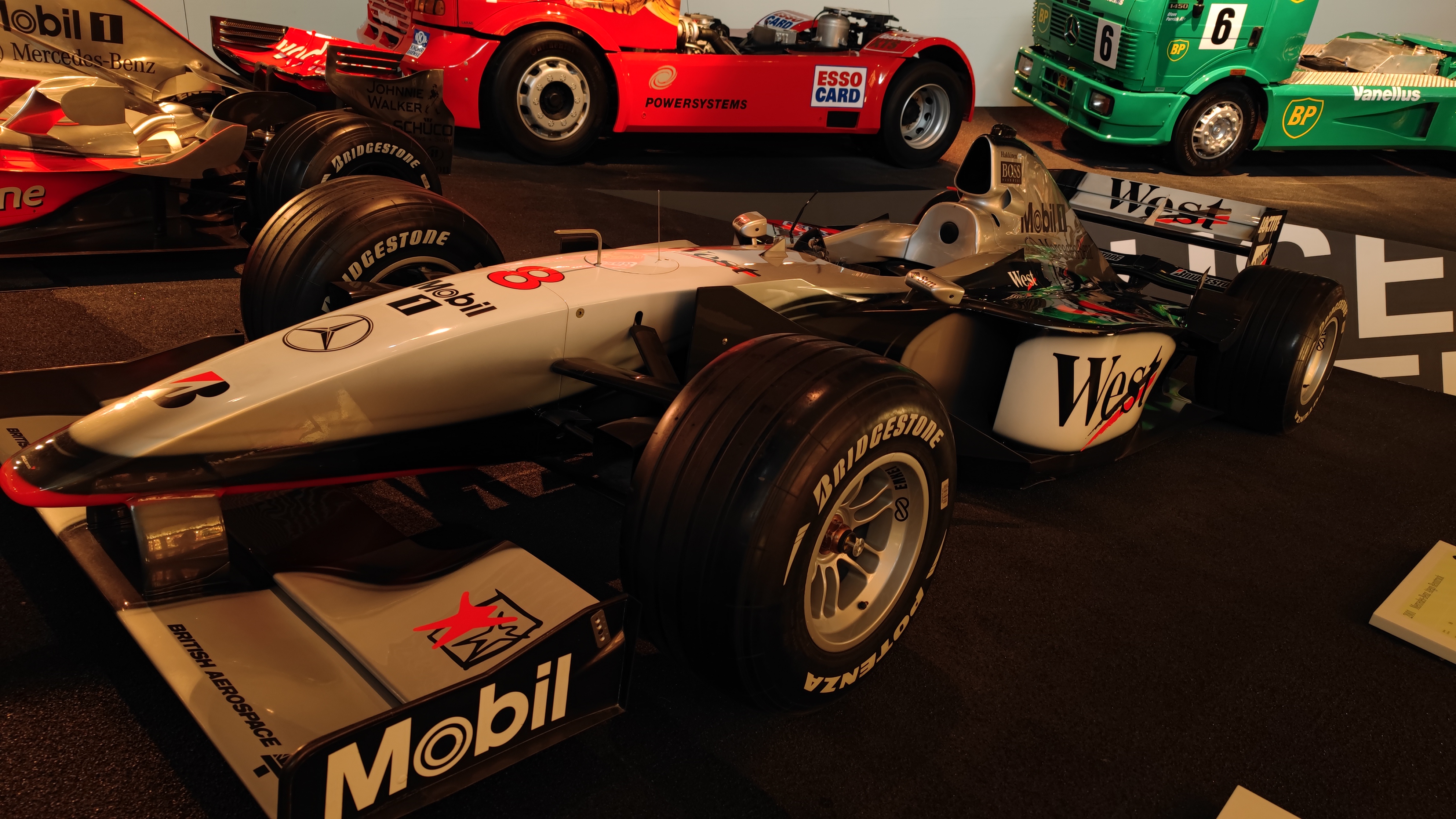 Exhibition of Formula-1 and other race cars in a museum.